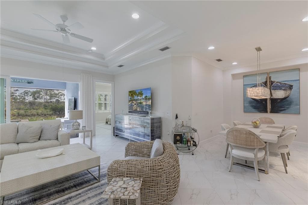 Living room featuring ceiling fan, a raised ceiling, and crown molding
