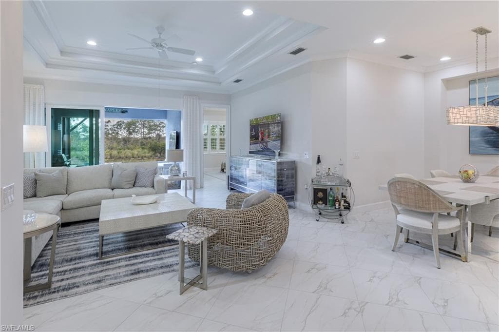 Living room featuring ceiling fan, crown molding, and a tray ceiling