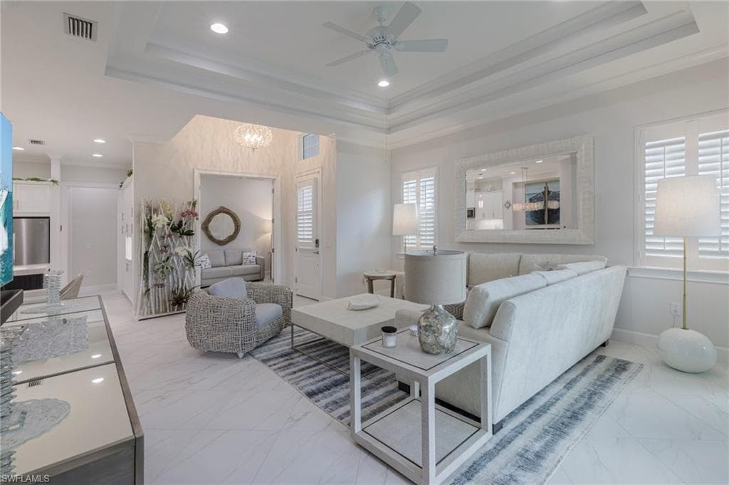 Living room featuring a raised ceiling, ornamental molding, and a wealth of natural light