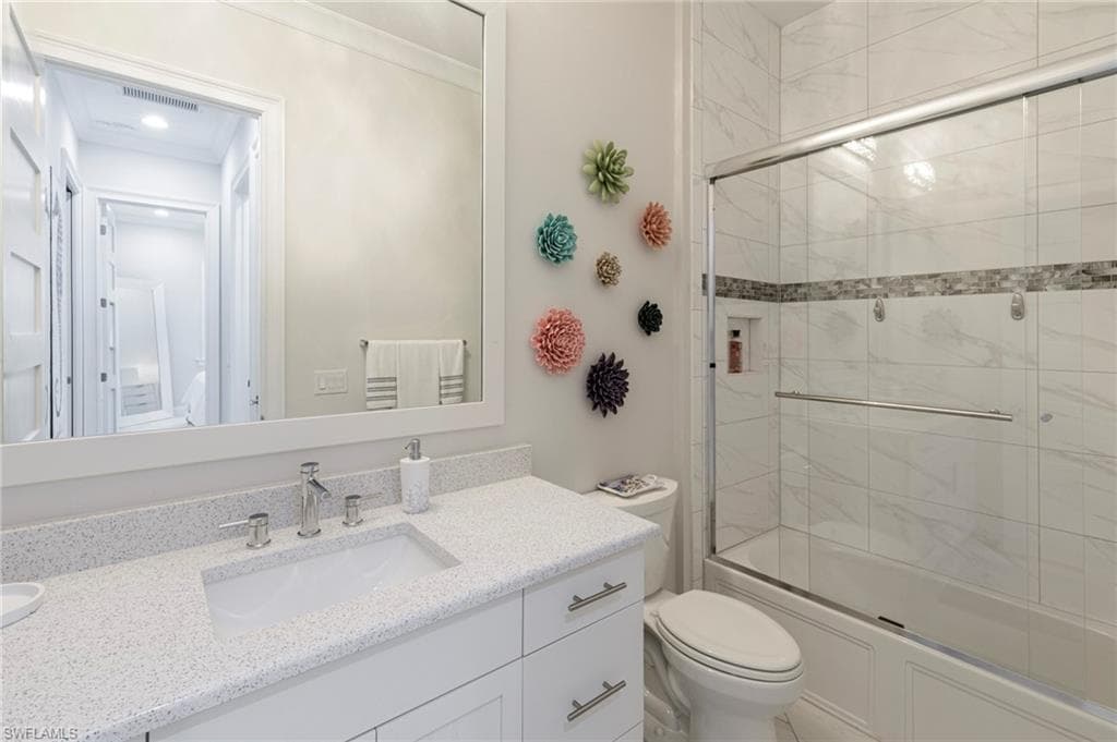 Full bathroom featuring shower / bath combination with glass door, vanity, and toilet