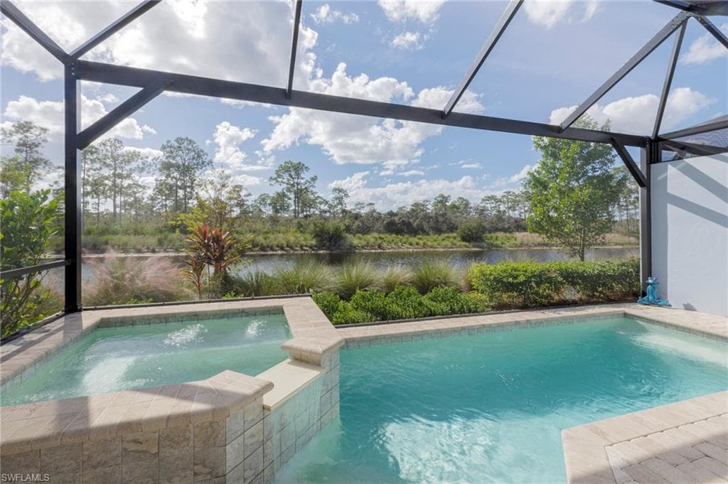 View of pool featuring a lanai, a water view, and an in ground hot tub
