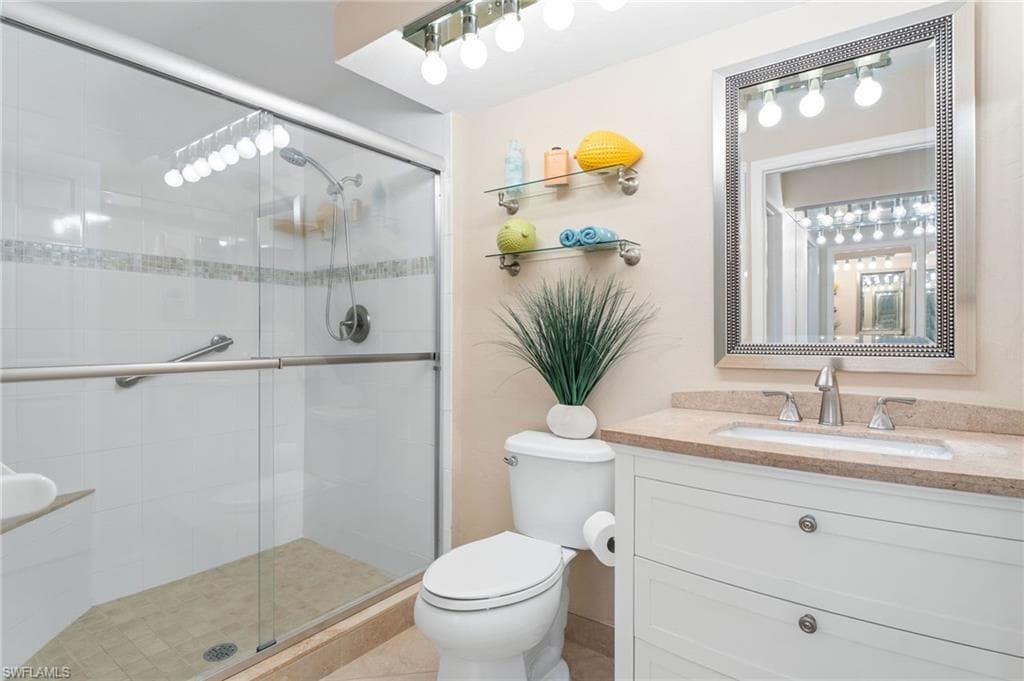 Bathroom with tile patterned floors, a shower with door, vanity, and toilet