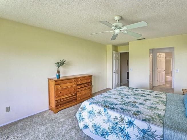 Bedroom with carpet flooring, a textured ceiling, a ceiling fan, and ensuite bathroom