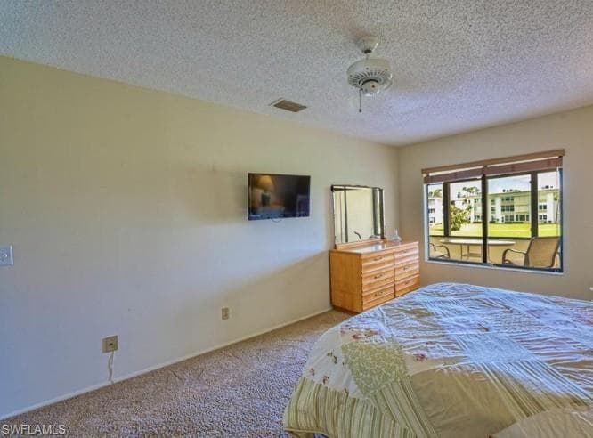 Bedroom featuring carpet, a textured ceiling, and ceiling fan
