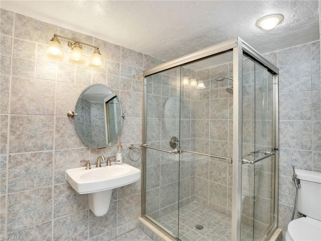 Bathroom featuring tile walls and toilet
