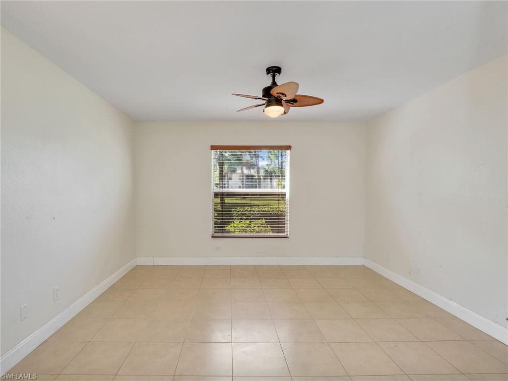 Empty room with light tile patterned floors and ceiling fan