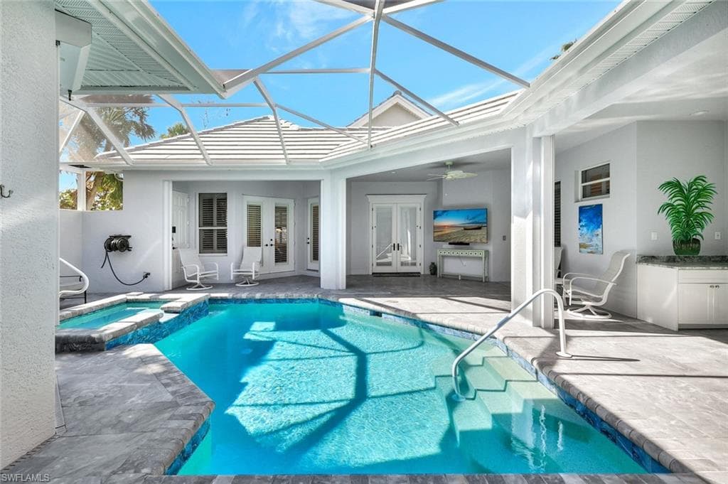 View of pool featuring french doors, ceiling fan, a lanai, an in ground hot tub, and a patio area