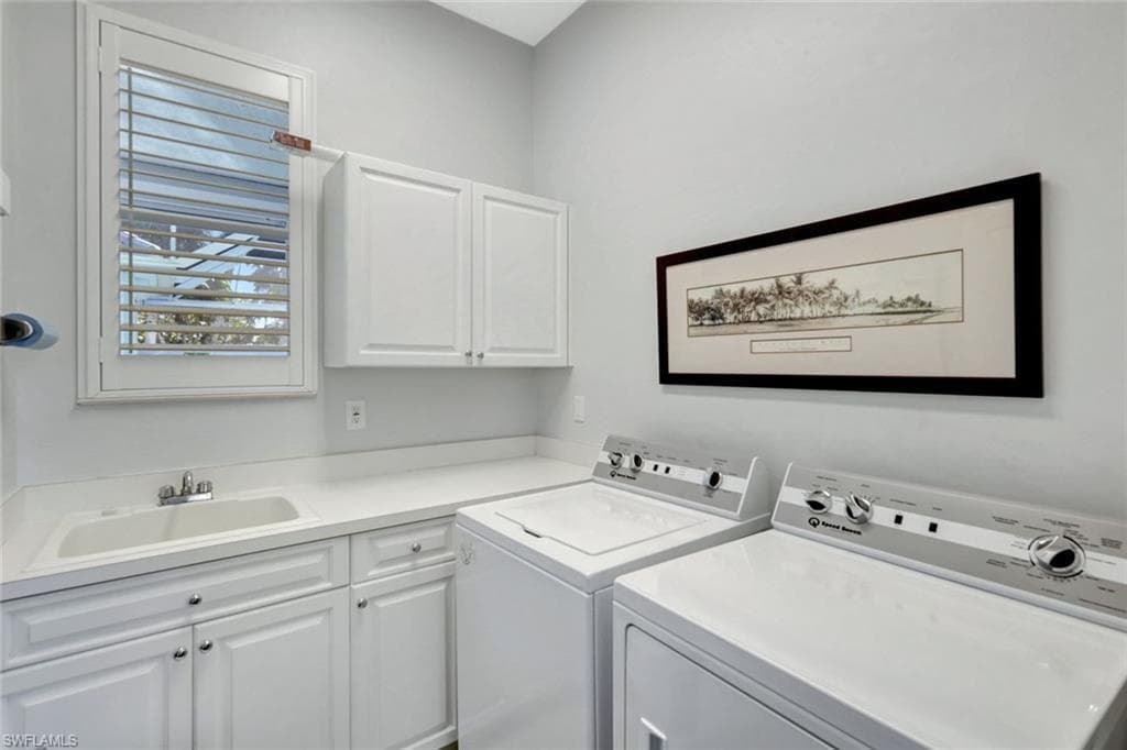 Clothes washing area with washing machine and dryer, sink, and cabinets