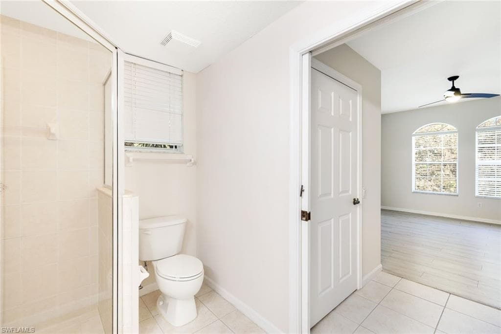 Bathroom with an enclosed shower, wood-type flooring, toilet, and ceiling fan