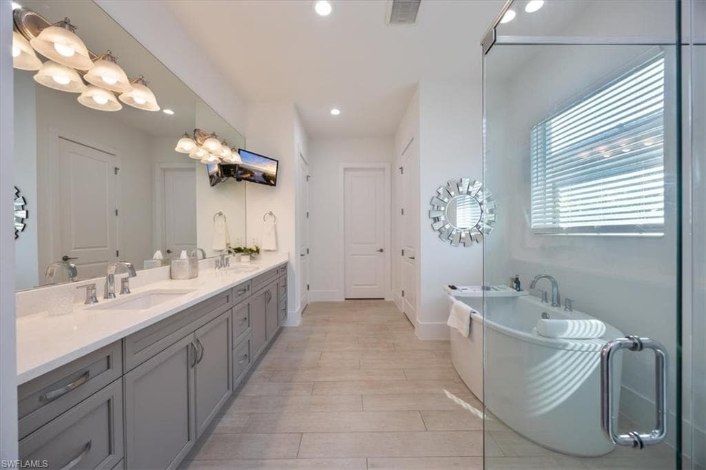 Luxurious primary bathroom with frameless glass shower and bathtub and TV is included