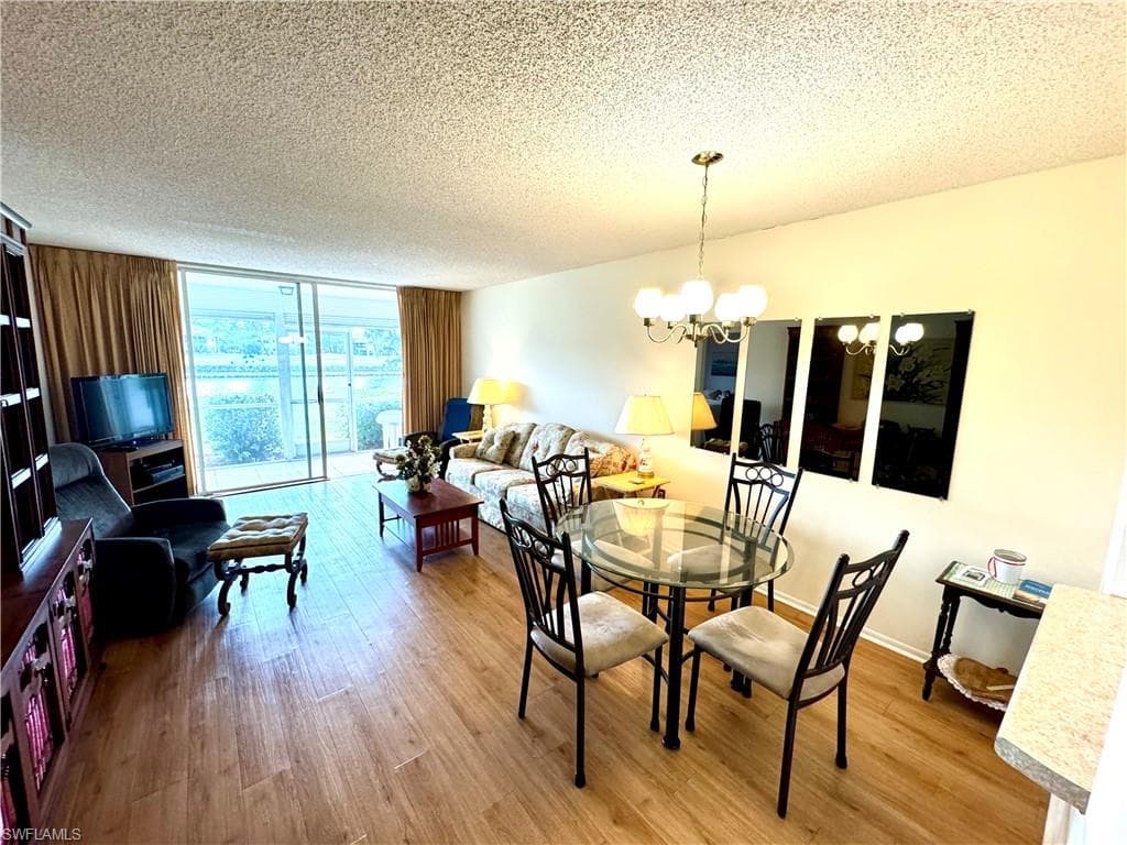 Dining area featuring expansive windows, wood-type flooring, a textured ceiling, and an inviting chandelier