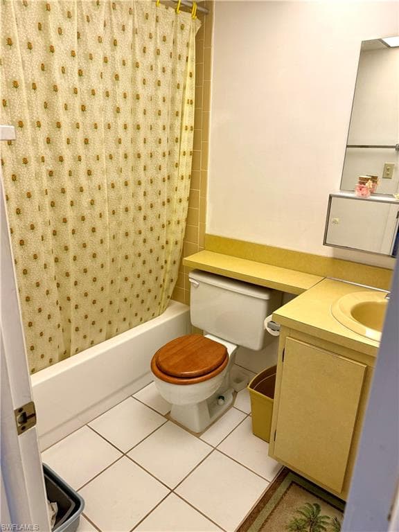 Full bathroom with tile patterned floors, vanity, toilet, and shower / bath combo with shower curtain