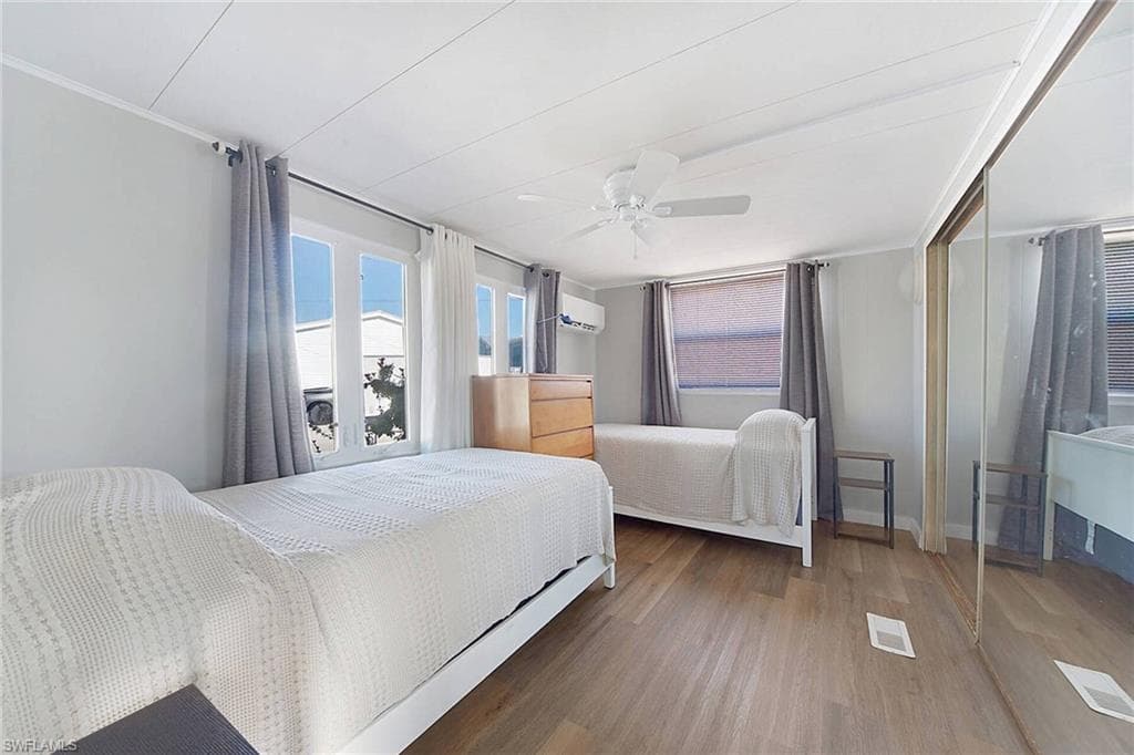 Bedroom with dark hardwood / wood-style flooring, an AC wall unit, and ceiling fan