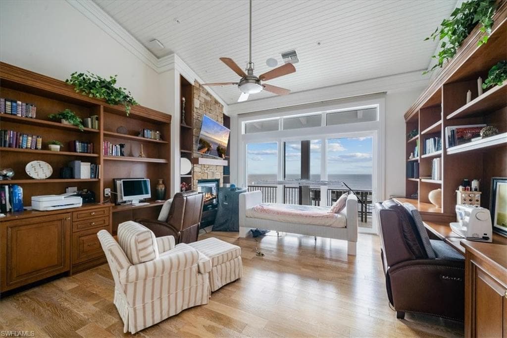 Office area with light hardwood / wood-style flooring, a fireplace, built in desk, ornamental molding, and wooden ceiling