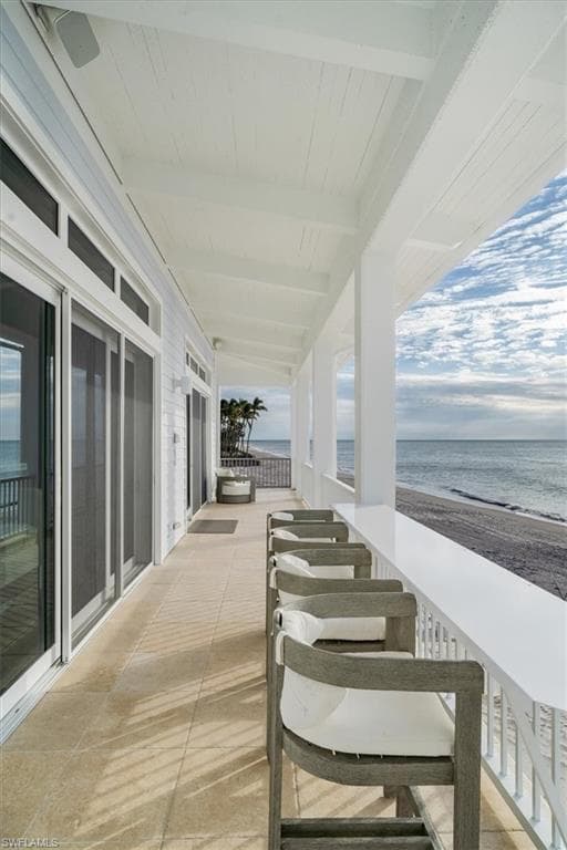 View of porch with a beach view and a water view