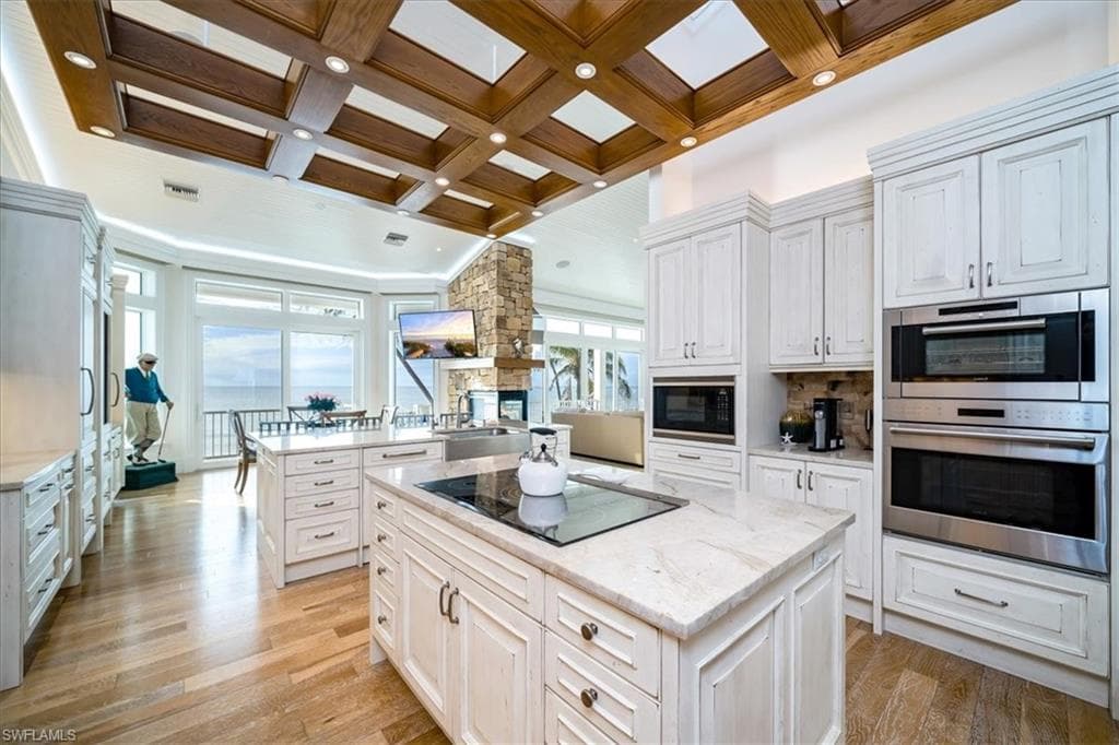 Kitchen with coffered ceiling, a center island, and white cabinets