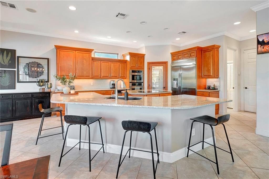Kitchen with sink, a kitchen bar, a large island with sink, stainless steel appliances, and light granite countertops