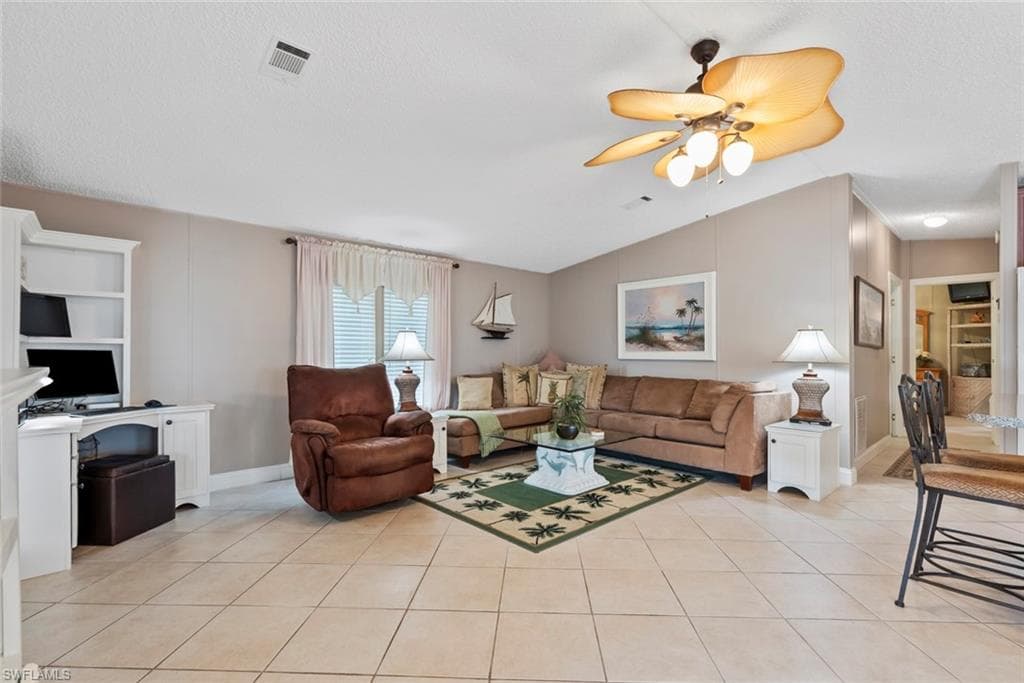 Tiled living room featuring ceiling fan, built in features, lofted ceiling