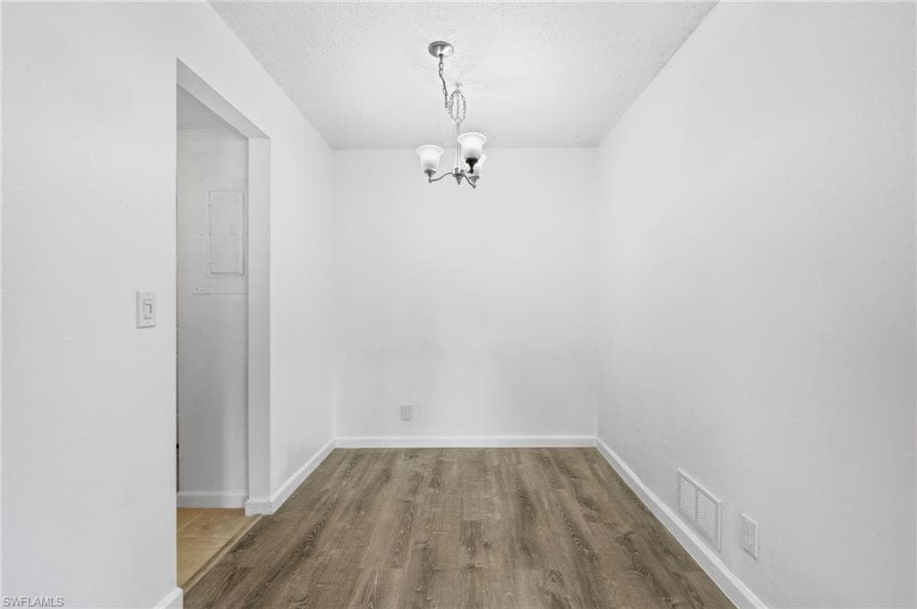 Unfurnished dining area with LVP wood-style floors and an inviting chandelier
