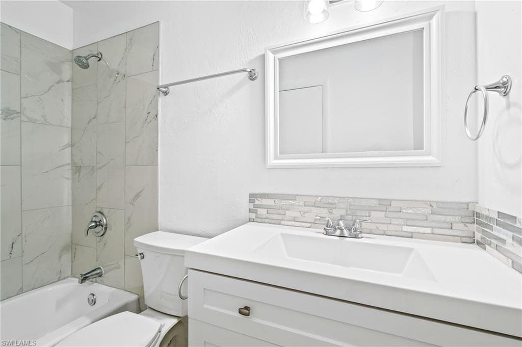 Full bathroom featuring vanity, tiled shower / bath combo, tasteful backsplash, and toilet. Second Floor.