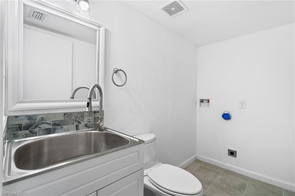 Bathroom with tile patterned floors, vanity, and toilet. Washer Dryer Hook up. First Floor Bathroom