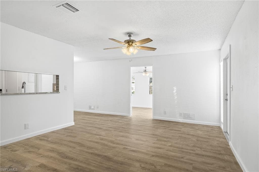 Unfurnished living room featuring ceiling fan, LVP wood-style floors, and a textured ceiling