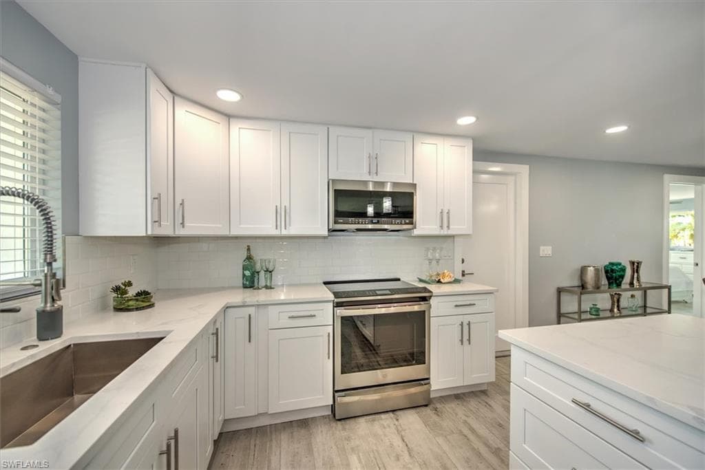 Kitchen featuring appliances with stainless steel finishes, white cabinetry, and sink