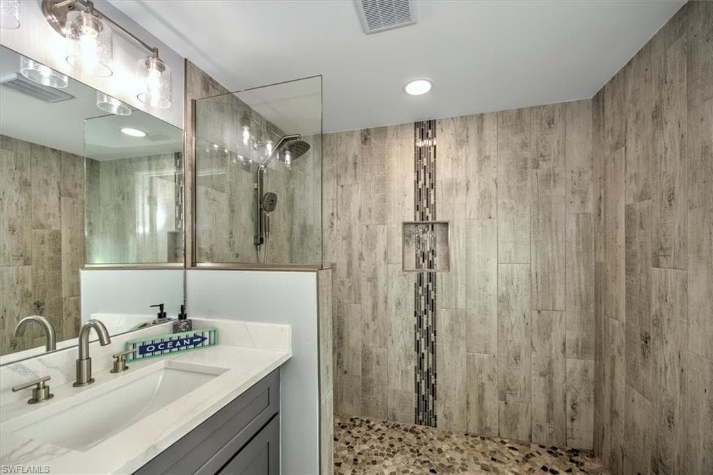 Bathroom featuring a tile shower and vanity