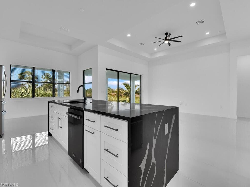 Kitchen featuring white cabinetry, a raised ceiling, and sink