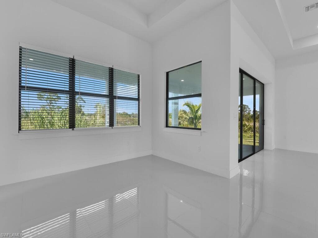 Tiled empty room with a raised ceiling and plenty of natural light