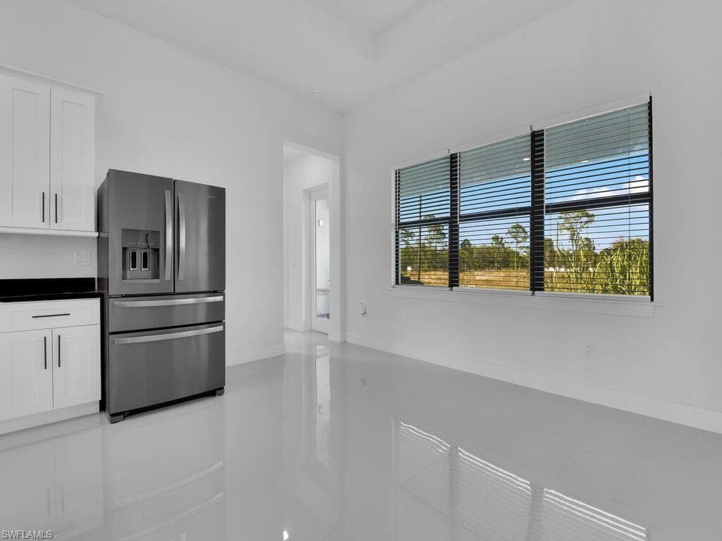 Kitchen with stainless steel fridge, plenty of natural light, and white cabinetry