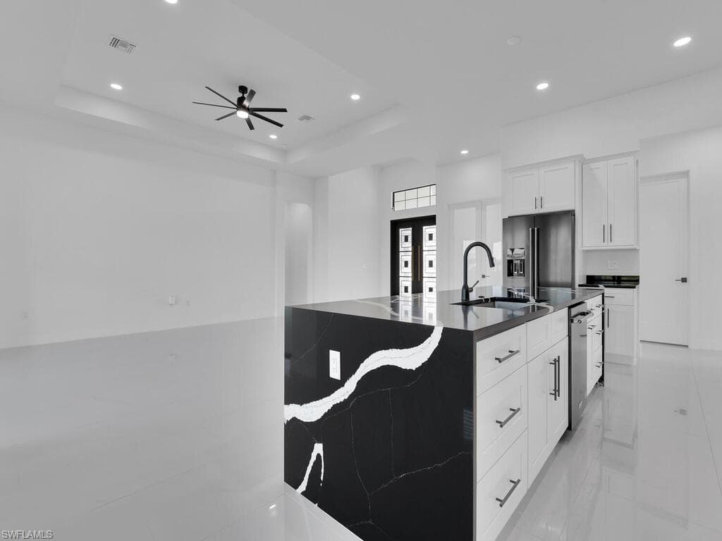 Kitchen featuring stainless steel dishwasher, high quality fridge, a tray ceiling, and white cabinetry