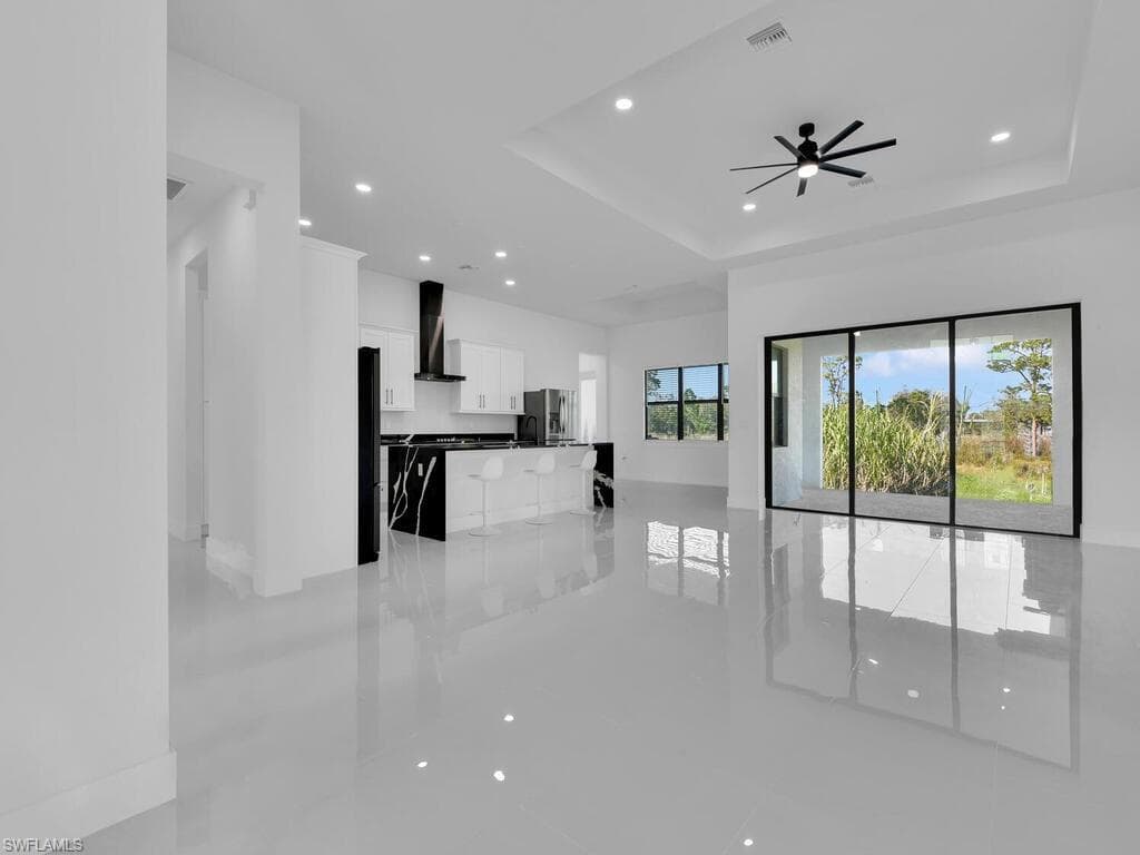 Unfurnished living room with ceiling fan and a tray ceiling