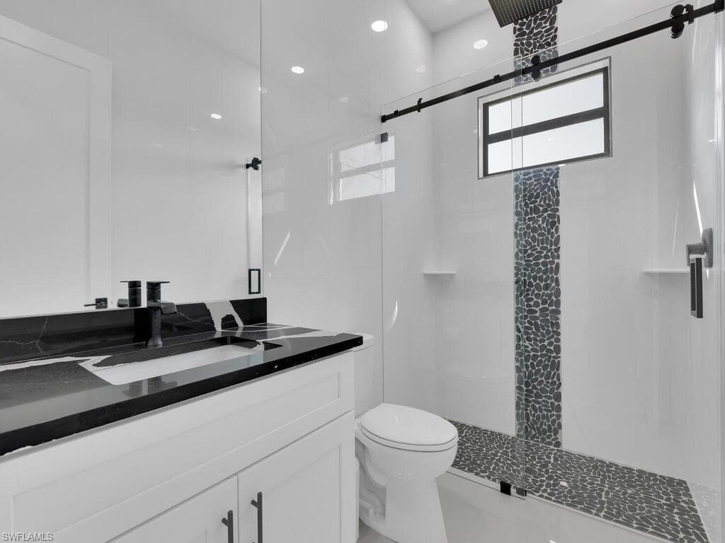 Bathroom featuring a shower with shower door, vanity, and toilet