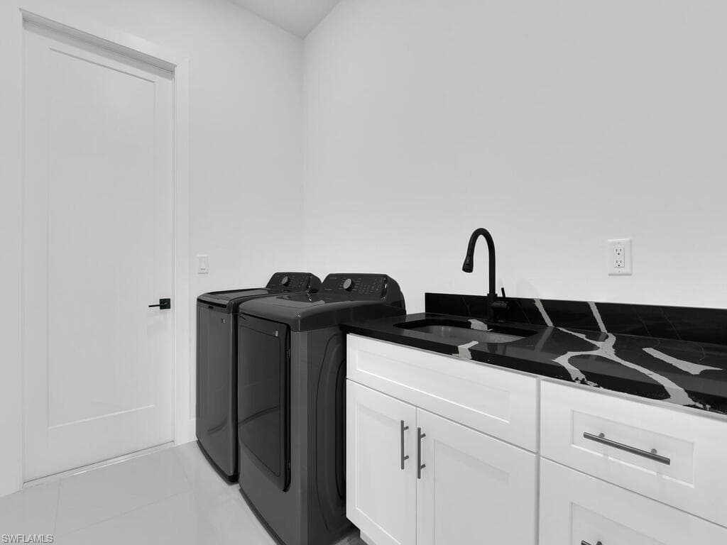 Clothes washing area featuring cabinets, light tile patterned flooring, separate washer and dryer, and sink