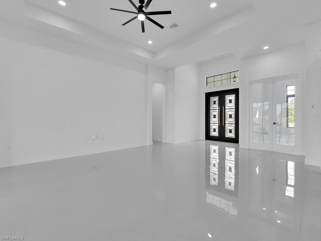 Tiled entryway featuring ceiling fan, french doors, and a tray ceiling