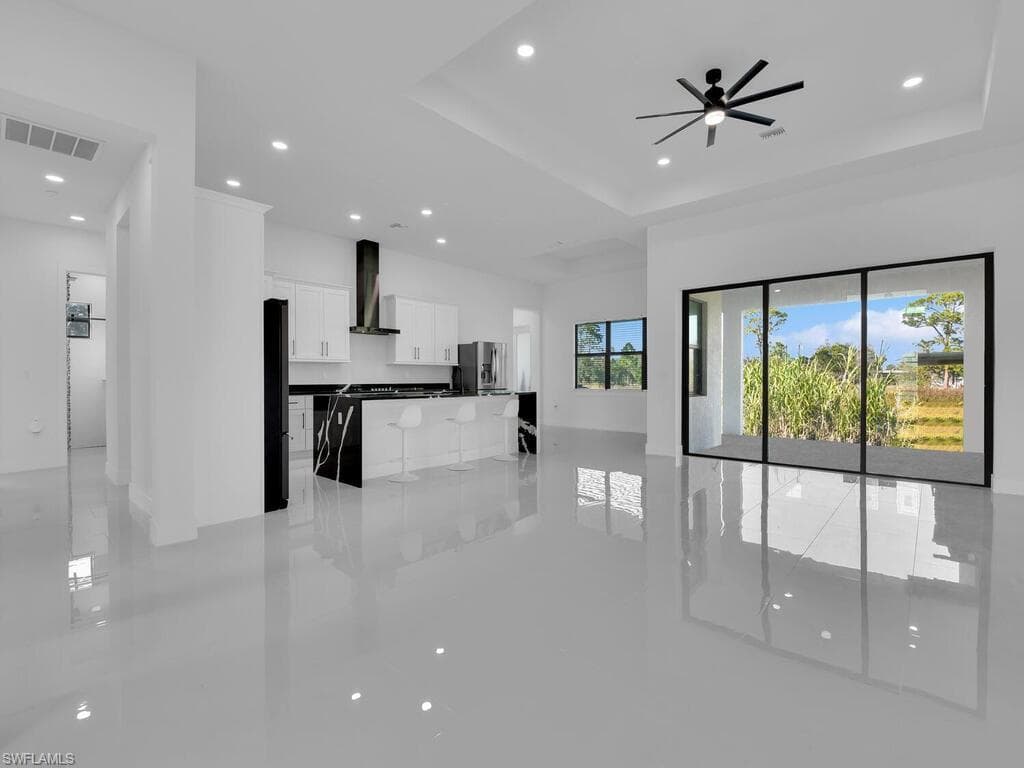 Unfurnished living room with ceiling fan and a raised ceiling