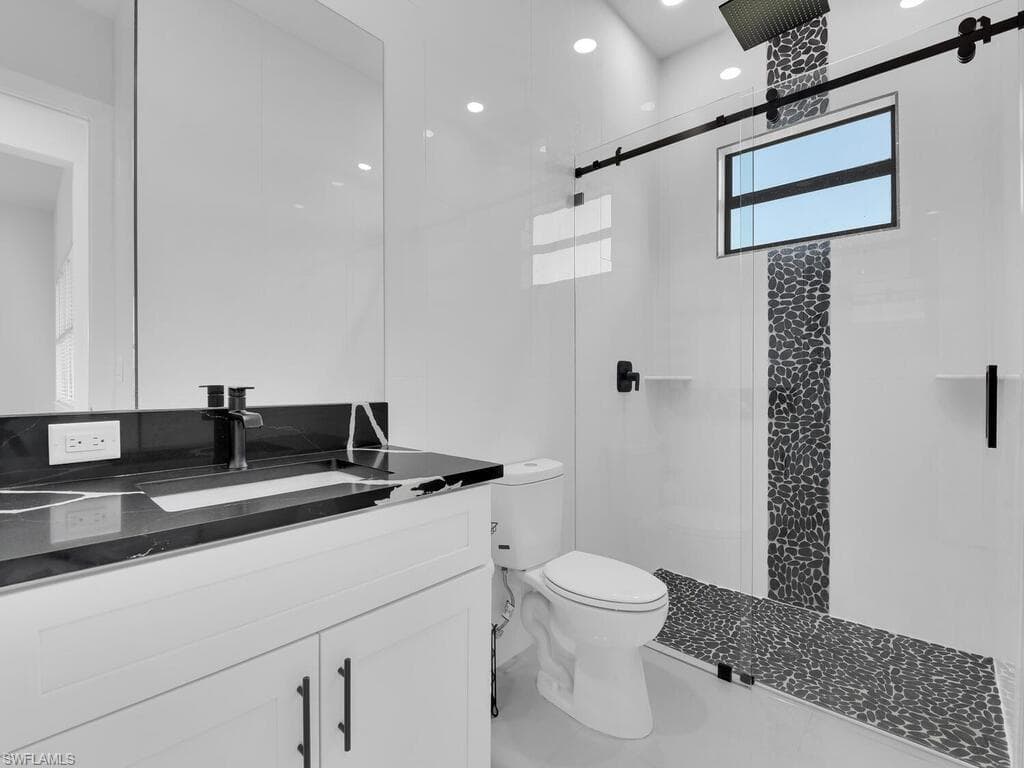 Bathroom with an enclosed shower, vanity, and toilet