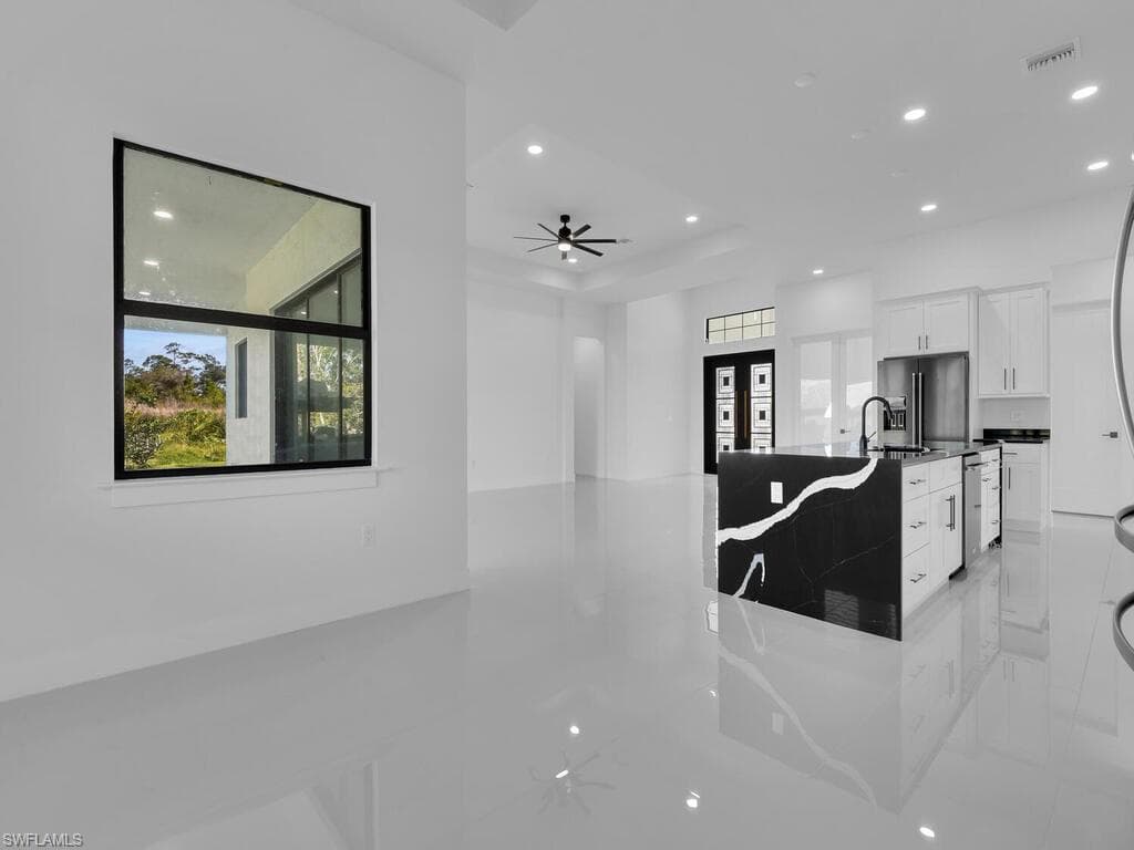 Kitchen with ceiling fan, white cabinetry, dark stone countertops, and dishwasher