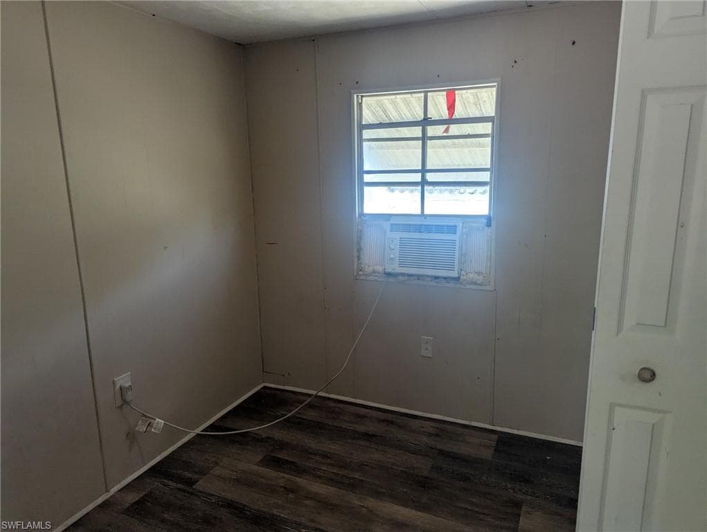 Spare room with dark wood-style flooring and cooling unit