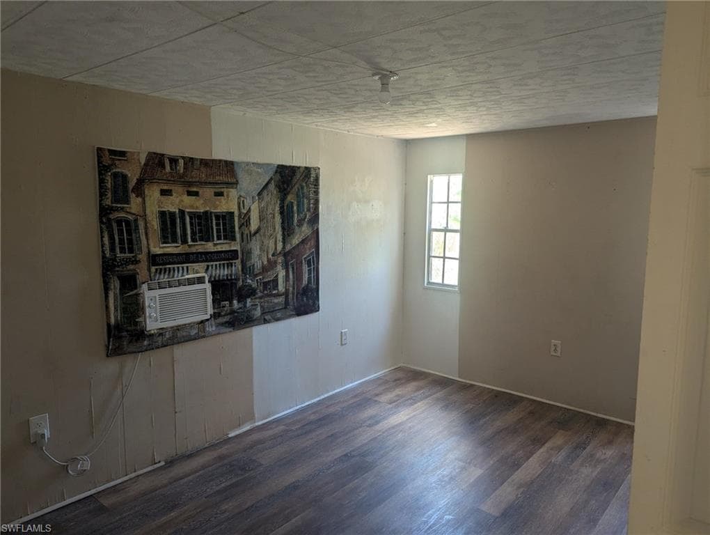 Unfurnished room with cooling unit and wood finished floors