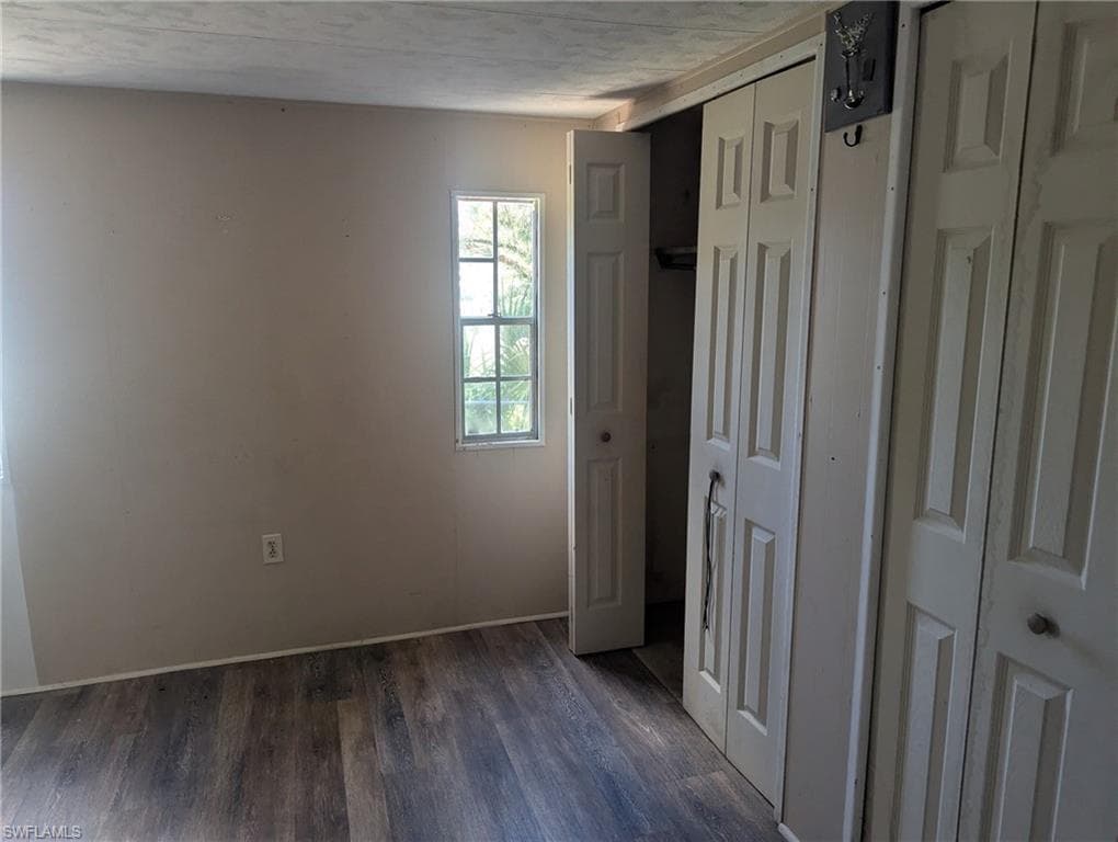 Unfurnished bedroom with baseboards and dark wood finished floors