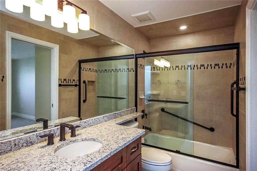 Full bathroom with toilet, enclosed tub / shower combo, and vanity