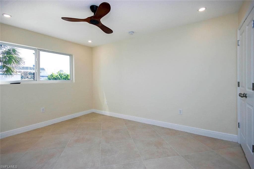 Tiled empty room featuring ceiling fan