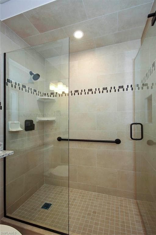 Bathroom featuring a shower with door and toilet