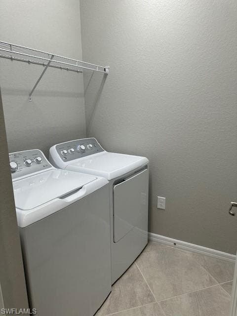Laundry area (upstairs) with washer and clothes dryer and light tile patterned flooring
