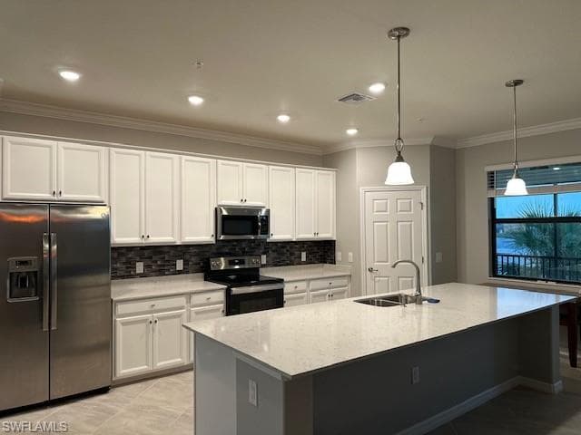 Kitchen with sink, hanging light fixtures, stainless steel appliances, white cabinets, and a center island with sink