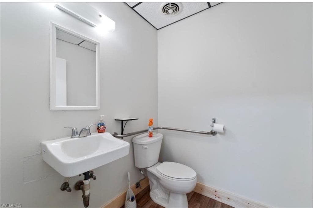 Half bath with toilet and wood finished floors