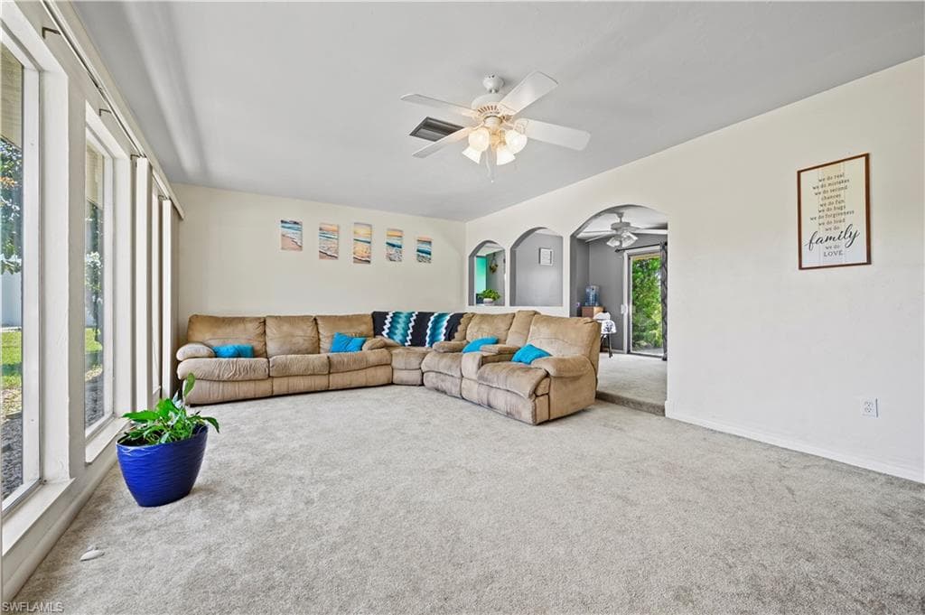 Carpeted living room featuring ceiling fan