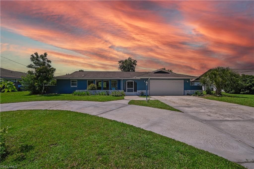 Single story home with a garage and a lawn